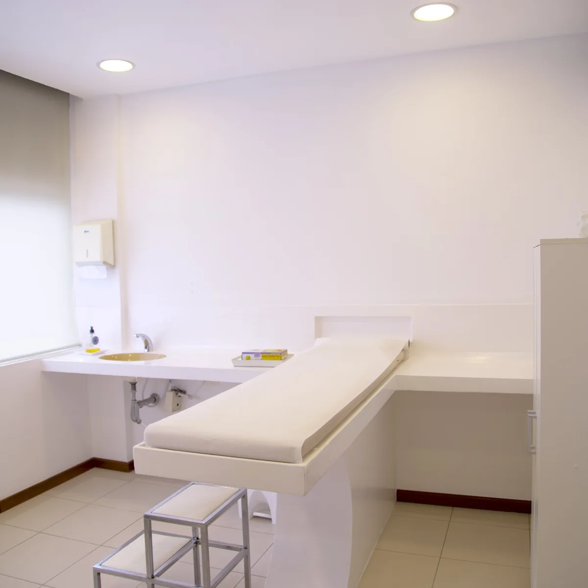 A bright, empty treatment room with an examination bed.